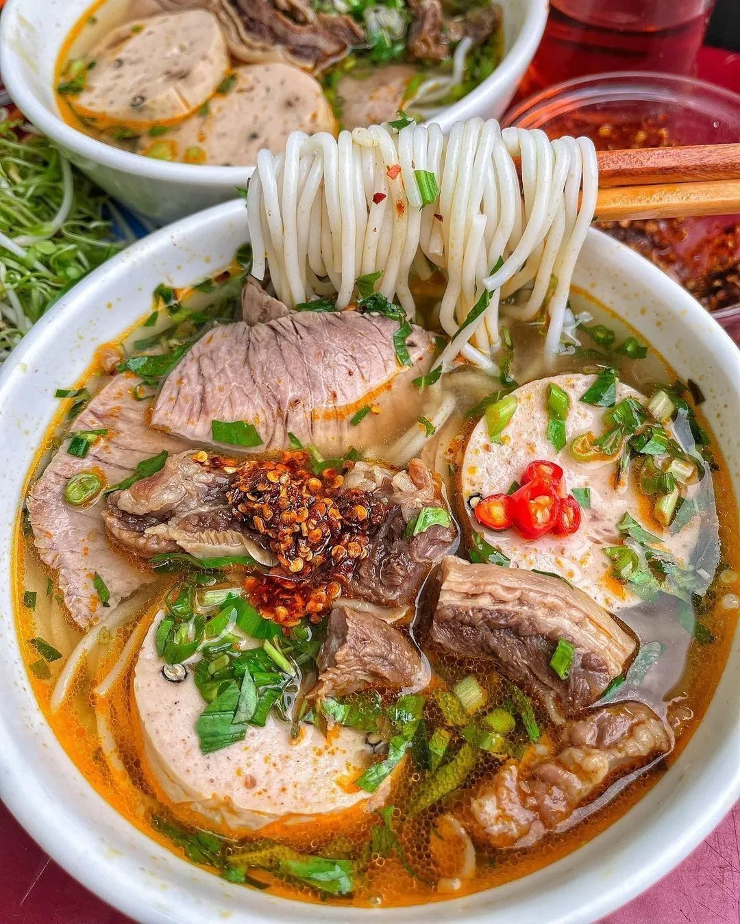 Tô bún bò Huế nóng hổi với nước dùng đậm đà, thịt bò, chả cua, rau sống và hương vị đặc trưng của ẩm thực cố đô