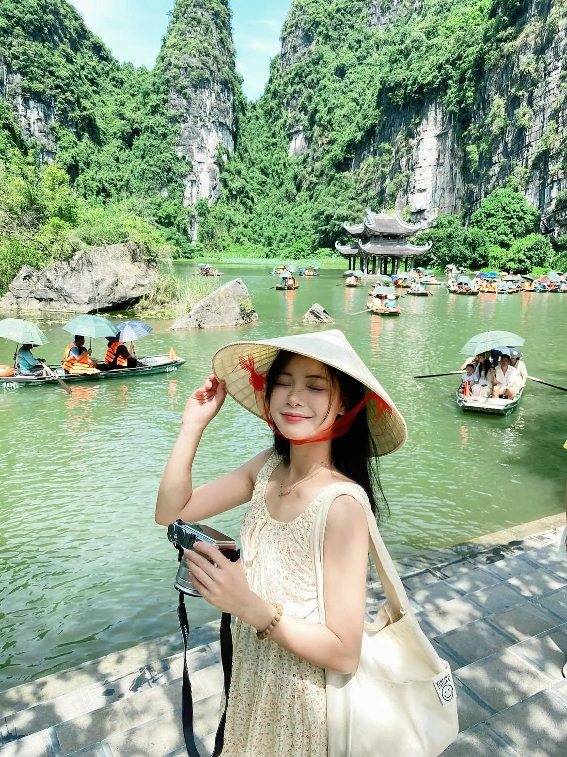 Khung cảnh Ninh Bình với núi đá vôi hùng vĩ, dòng sông xanh uốn lượn và thuyền du lịch giữa thiên nhiên yên bình.